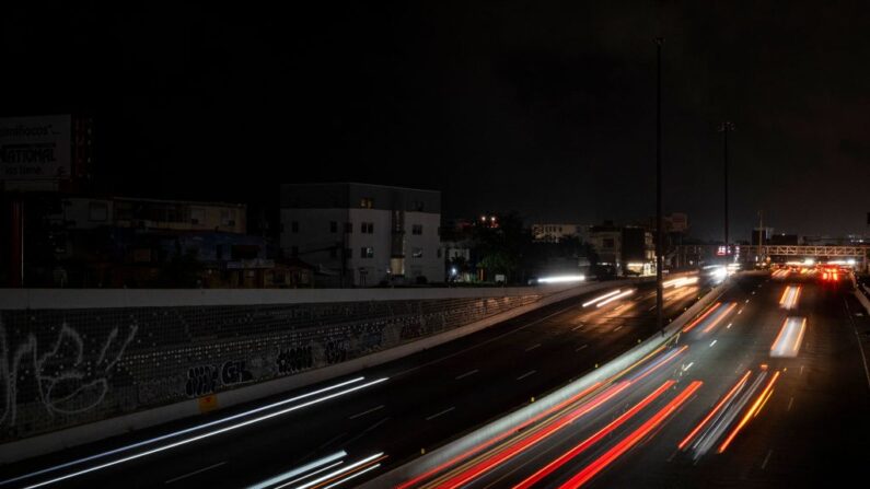 Los coches circulan por una carretera concurrida y oscura mientras la ciudad queda a oscuras por un corte de energía en el Viejo San Juan, Puerto Rico, el 10 de junio de 2021. (Ricardo Arduengo/AFP vía Getty Images)