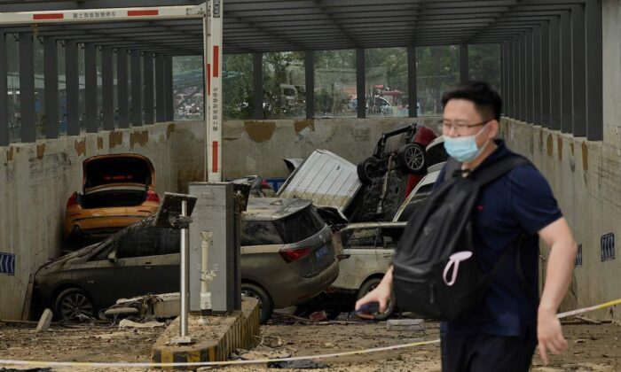El 24 de julio de 2021, un hombre pasa frente a un estacionamiento con vehículos apilados unos sobre otros después de fuertes lluvias que causaron inundaciones días antes. Durante las torrenciales lluvias murieron al menos 56 personas en la ciudad de Zhengzhou, provincia china de Henan. (Noel Celis/AFP a través de Getty Images)