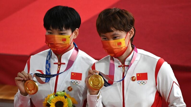 Las medallistas de oro, la china Bao Shanju (i) y la china Zhong Tianshi, posan con sus medallas en el podio tras la final de sprint por equipos de ciclismo en pista femenino durante los Juegos Olímpicos de Tokio 2020 en el Velódromo de Izu, Japón, el 2 de agosto de 2021. (Greg Baker/AFP vía Getty Images)