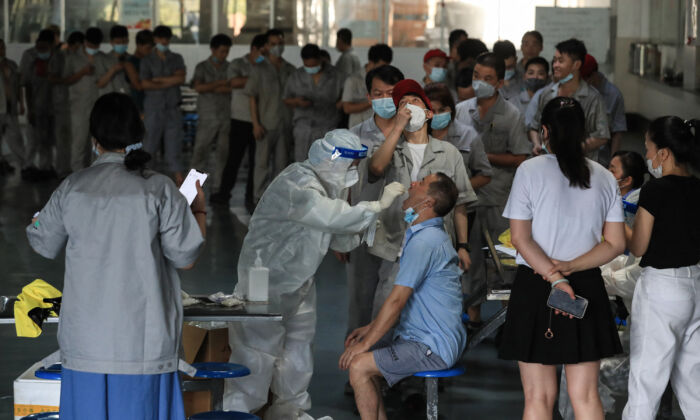 Un trabajador se somete a un test de COVID-19 en el comedor de una fábrica de piezas de automóviles en Wuhan, en la provincia central china de Hubei, el 4 de agosto de 2021. (STR/AFP vía Getty Images)