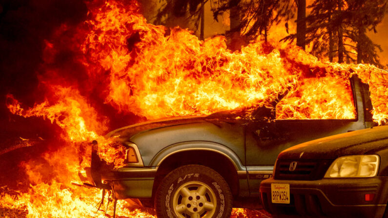 Vehículos y una casa están envueltos en llamas mientras el incendio Dixie hace estragos en Greenville, California (EE.UU.), el 5 de agosto de 2021. (Josh Edelson/AFP vía Getty Images)