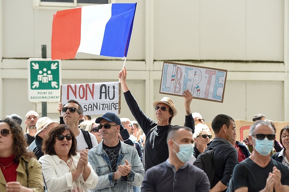 Un manifestante sostiene una bandera francesa y una pancarta en la que se lee "Libertad", durante una jornada nacional de protesta contra la vacunación obligatoria de Covid-19 para ciertos trabajadores y el uso obligatorio de la tarjeta sanitaria convocada por el gobierno francés en Nantes, oeste de Francia, el 7 de agosto de 2021. (Foto de SEBASTIEN SALOM-GOMIS/AFP a través de Getty Images)