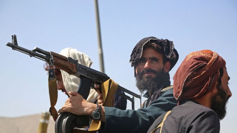 Unos terroristas talibanes montan guardia en un vehículo al borde de la carretera en Kabul el 16 de agosto de 2021, después de un final sorprendentemente rápido de la guerra de 20 años en Afganistán, mientras miles de personas se agolpan en el aeropuerto de la ciudad tratando de huir de la temida línea dura del grupo terrorista islamista. (Foto de - / AFP)