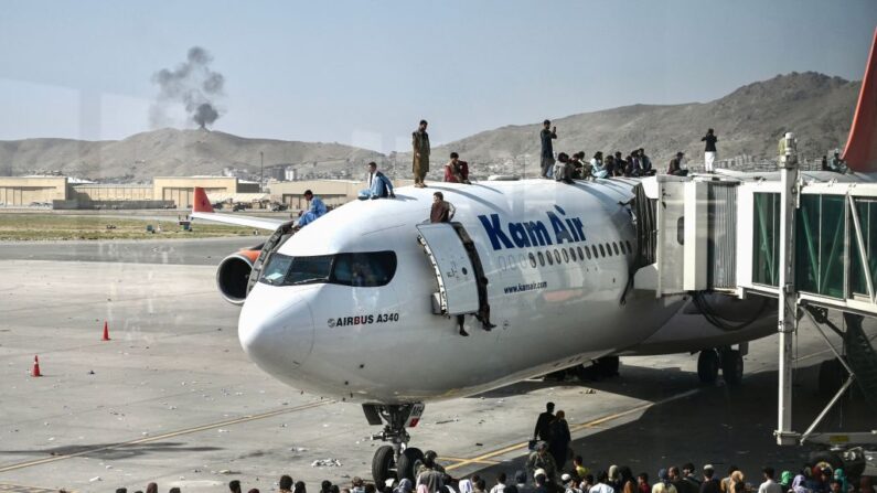Varios afganos se suben a un avión mientras esperan en el aeropuerto de Kabul el 16 de agosto de 2021. (Wakil Kohsar/AFP vía Getty Images)