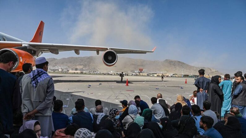 Los afganos se sientan mientras esperan para abandonar del aeropuerto de Kabul el 16 de agosto de 2021. Después de un final asombrosamente rápido de la guerra de 20 años de Afganistán, miles de personas entraron en el aeropuerto de la ciudad tratando de huir de los terroristas talibanes. (Wakil Kohsar / AFP vía Getty Images)