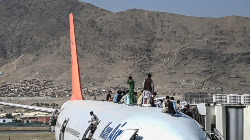 Varios afganos suben a un avión mientras esperan en el aeropuerto de Kabul el 16 de agosto de 2021, después de un sorprendente y rápido final de la guerra de 20 años en Afganistán, cuando miles de personas se agolparon en el aeropuerto de la ciudad tratando de huir del temido régimen islamista de los talibanes. (Foto de WAKIL KOHSAR/AFP vía Getty Images)