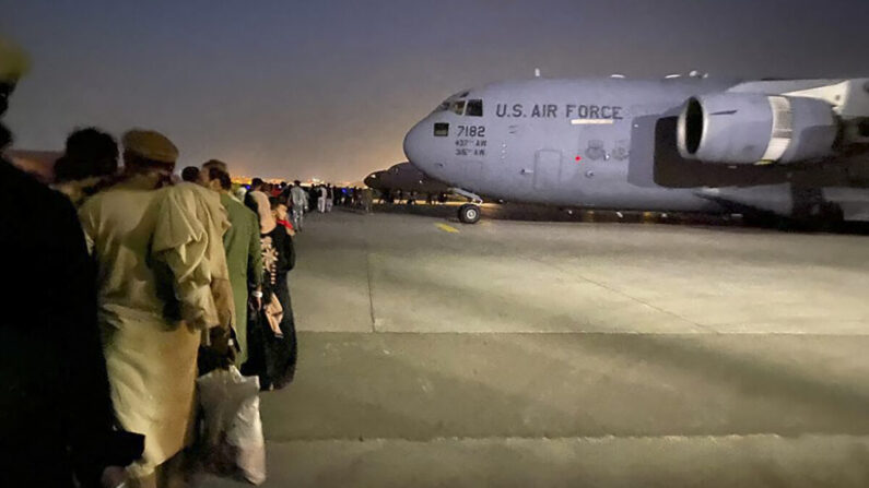 Los afganos hacen fila y suben a un avión militar estadounidense para abandonar Afganistán, en el aeropuerto militar de Kabul, el 19 de agosto de 2021. (Shakib Rahmani/AFP vía Getty Images)