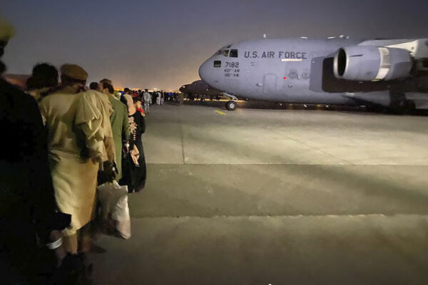 Decenas de afganos hacen cola para subir a un avión militar de EE. UU. para salir de Afganistán en el aeropuerto militar de Kabul el 19 de agosto de 2021, tras la toma de Afganistán por los talibanes. (Shakib Rahmani/AFP vía Getty Images)