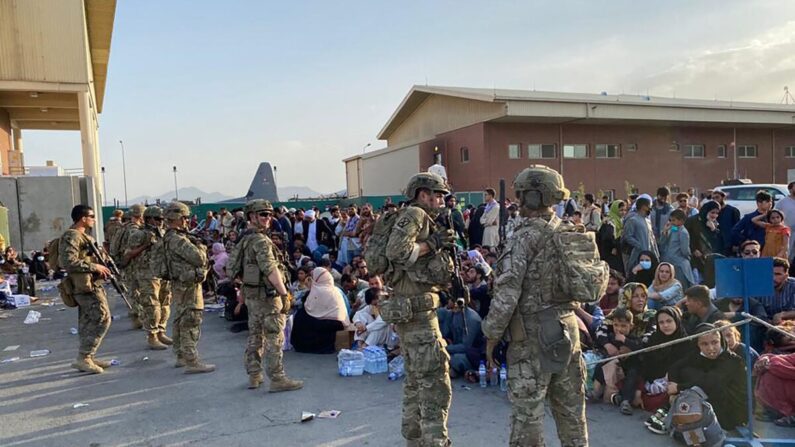 Soldados estadounidenses montan guardia mientras grupos de afganos esperan para subir a un avión militar estadounidense con el propósito de salir de Afganistán, en el aeropuerto militar de Kabul, el 19 de agosto de 2021. (Shakib Rahmani/AFP vía Getty Images)