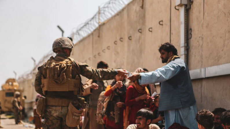 Un infante de marina con la 24a Unidad Expedicionaria de los Infantes de Marina (MEU) pasa agua a los evacuados durante la evacuación en el Aeropuerto Internacional Hamid Karzai durante la evacuación el 21 de agosto de 2021 en Kabul, Afganistán. (Isaiah Campbell/U.S. Marine Corps a través de Getty Images)