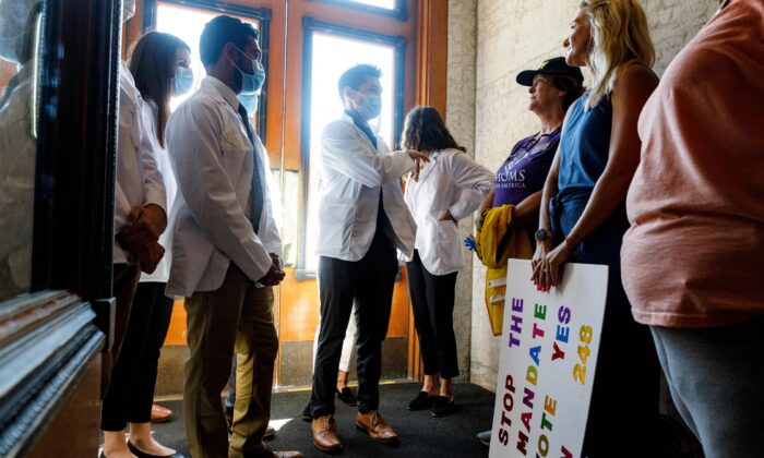 Andrew (C), de 24 años, estudiante de medicina de la Universidad Estatal de Ohio, discute la Ley de Elección de Vacunas y Antidiscriminación con personas que apoyan la ley en el interior de la Casa del Estado de Ohio en Columbus, Ohio, el 24 de agosto de 2021. (Stephen Zenner/AFP vía Getty Images)