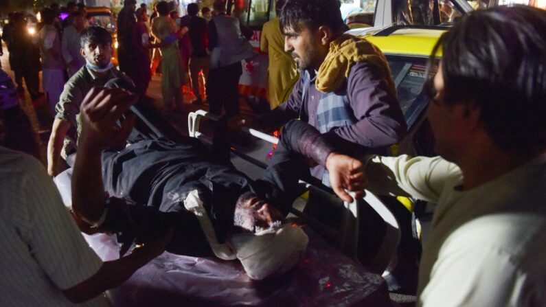 Personal médico y hospitalario lleva a un hombre herido en una camilla para ser tratado después de dos explosiones, que mataron al menos a 6 e hirieron a una docena, fuera del aeropuerto en Kabul (Afganistán) el 26 de agosto de 2021. (Wakil Kohsar/AFP vía Getty Images)