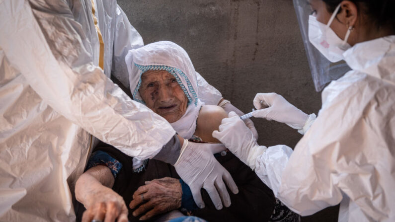 La enfermera Bilge Koc (d) del equipo de vacunación del Centro de Salud Pública de Gevas administra la vacuna china Sinovac Coronavac a Feride Payza, de 99 años, durante una visita domiciliaria en el pueblo de Daldere el 12 de febrero de 2021 en Van, Turquía.  (Chris McGrath/Getty Images)