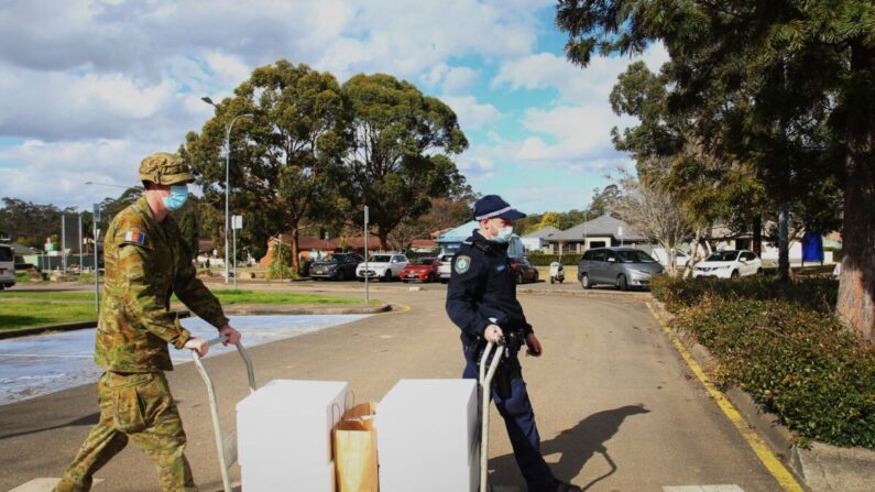 El personal de la Fuerza de Defensa Australiana y la policía de Nueva Gales del Sur cargan paquetes de alimentos para entregarlos a las personas en confinamiento en el Centro de Ocio Prairiewood el 2 de agosto de 2021 en Sídney, Australia. (Lisa Maree Williams / Getty Images)
