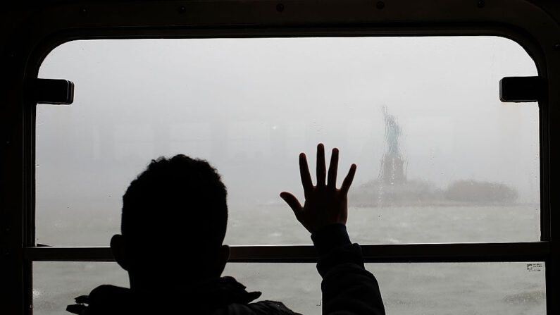 Un hombre mira la Estatua de la Libertad bajo la lluvia y la niebla desde el ferry de Staten Island, el 20 de abril de 2015, en la ciudad de Nueva York. (Spencer Platt/Getty Images)