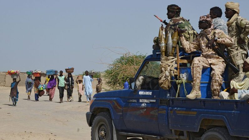 En una foto de archivo, habitantes de la ciudad nigeriana de Malam Fatori y su zona, cerca de las fronteras con Níger y Chad, pasan junto a un coche con gendarmes chadianos (en uniforme) mientras huyen de los ataques islamistas de Boko Haram para refugiarse en la ciudad nigeriana de Bosso, protegida por los ejércitos de Níger y Chad, el 25 de mayo de 2015. (Issouf Sanogo/AFP via Getty Images)