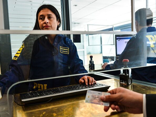 La policía aduanera revisa los pasaportes de los pasajeros que arriban a Chile, en un módulo protegido con cobre antimicrobiano en el Aeropuerto de Santiago el 28 de agosto de 2016. (MARTIN BERNETTI/AFP a través de Getty Images)