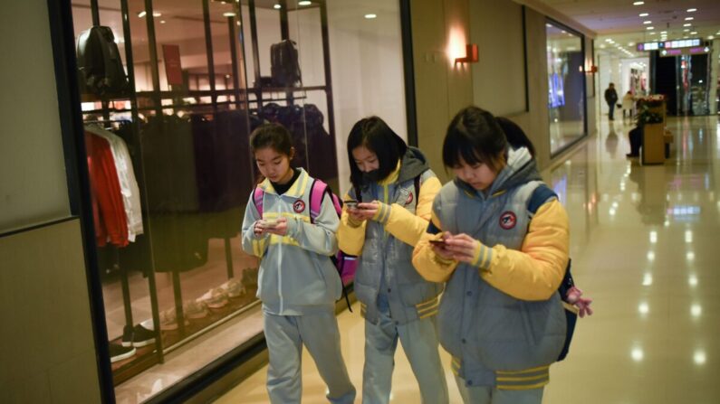 Los estudiantes usan sus celulares mientras caminan en un centro comercial en Beijing, China, el 26 de enero de 2018 (Wang Zhao / AFP a través de Getty Images). (Editado)Recuperar original