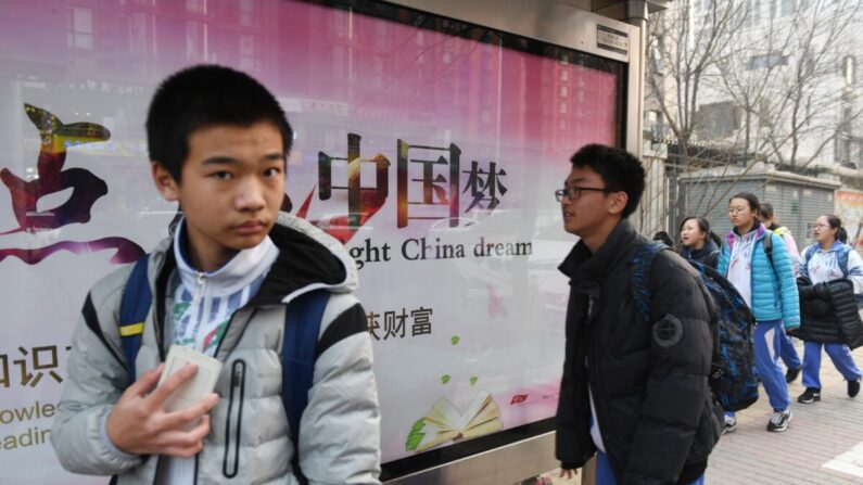 Jóvenes pasan frente a un cartel de propaganda sobre el "Sueño de China", un eslogan asociado con el presidente chino Xi Jinping, frente a una escuela en Beijing, el 12 de marzo de 2018. (Greg Baker/AFP a través de Getty Images)