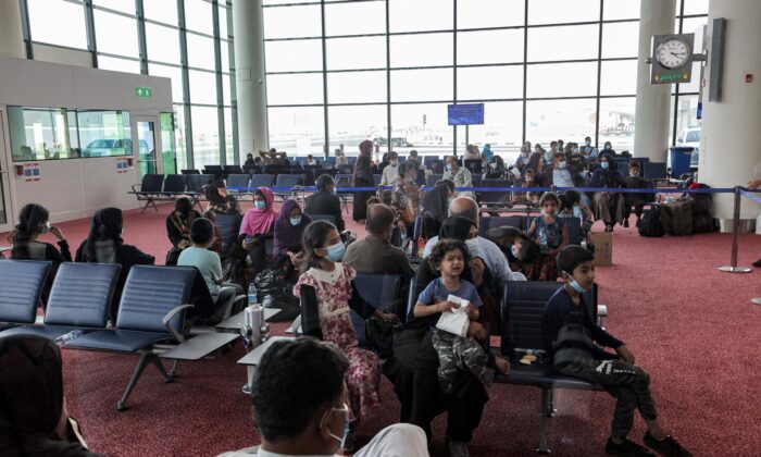 Los evacuados de Afganistán se sientan en una sala a su llegada al aeropuerto internacional Al Maktoum, en los Emiratos Árabes Unidos, el 19 de agosto de 2021. (Giuseppe Cacace/AFP a través de Getty Images)