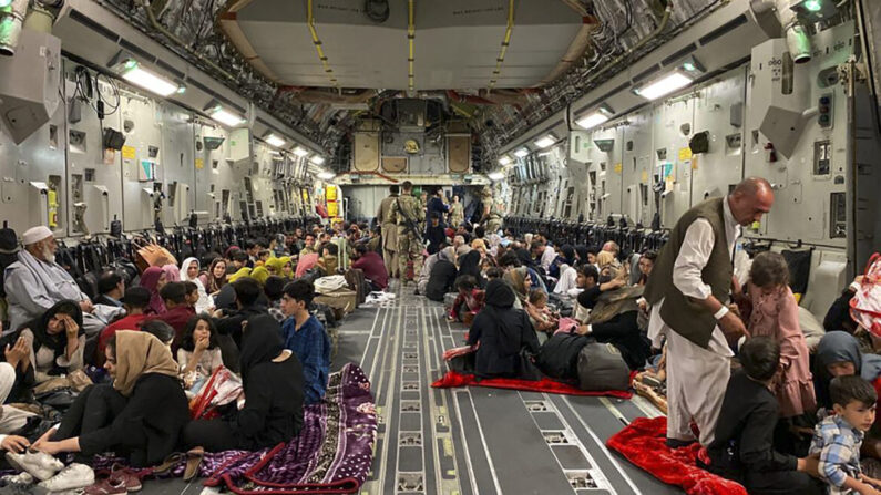 Los afganos se sientan dentro de un avión militar estadounidense para salir de Afganistán en el aeropuerto militar de Kabul el 19 de agosto de 2021 tras la toma de Afganistán por los talibanes. (Shakib Rahmani/AFP a través de Getty Images)