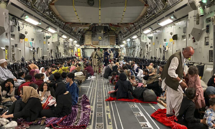 Varios afganos se sientan en el interior de un avión militar de EE. UU. para abandonar Afganistán, en el aeropuerto militar de Kabul el 19 de agosto de 2021 tras la toma militar de Afganistán por parte de los talibanes. (Shakib Rahmani/AFP vía Getty Images)