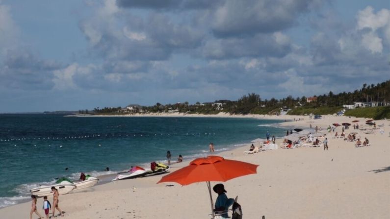 Un salvavidas se sienta bajo la sombrilla mientras observa a la gente disfrutar de la playa de Paradise island, Nassau, Bahamas, el 29 de abril de 2019. (Daniel Slim/AFP vía Getty Images)