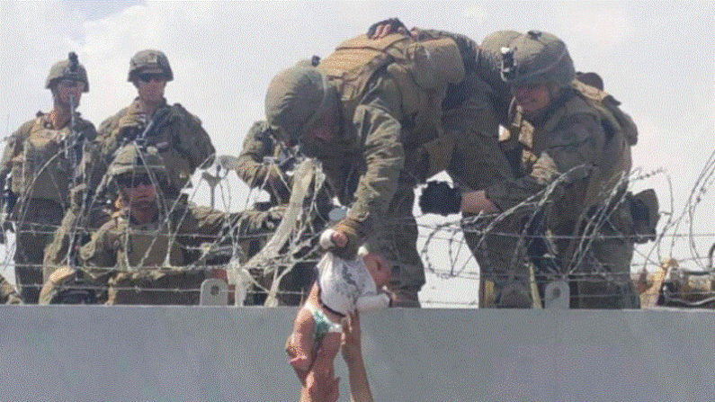 Esta imagen facilitada a la AFP el 20 de agosto de 2021 por Omar Haidiri, muestra a un marine estadounidense agarrando a un bebé por encima de una valla de alambre de espino durante una evacuación en el aeropuerto internacional Hamid Karzai de Kabul el 19 de agosto de 2021. (Cortesía de Omar Haidiri / AFP vía Getty Images)