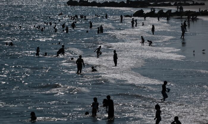 Con un aviso de calor en efecto, la gente se refresca en la playa de Coney Island en Brooklyn en la ciudad de Nueva York el 28 de junio de 2021. (Spencer Platt/Getty Images)