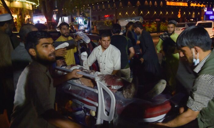 Voluntarios y personal médico llevan a un hombre herido hacia un hospital, en Kabul, después de las explosiones fuera del aeropuerto Hamid Karzai, en Afganistán, el 26 de agosto de 2021. (Wakil Kohsar/AFP a través de Getty Images)