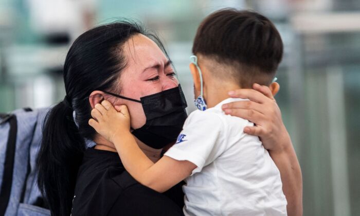 Una mujer abraza a un niño pequeño en las puertas de salida del aeropuerto internacional de Hong Kong el 19 de julio de 2021. (ISAAC LAWRENCE/AFP vía Getty Images)