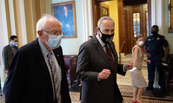 El senador Bernie Sanders (I-Vt.)(iz) camina con el líder de la mayoría del Senado, Chuck Schumer (D-N.Y.), después de reunirse para tratar sobre un presupuesto de 3.5 billones de dólares, en Washington el 9 de agosto de 2021. (Win McNamee/Getty Images)