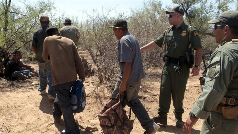 Fotografía de archivo donde se observa a dos miembros de la Patrulla Fronteriza auxiliando a un grupo de inmigrantes ilegales. EFE/Gary Williams