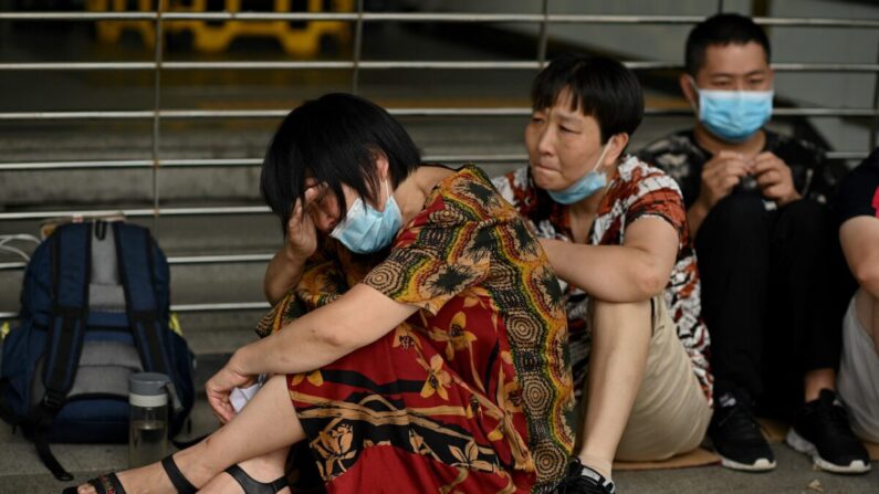 Una mujer llora mientras ella y otras personas se reúnen en la sede de Evergrande en Shenzhen, sureste de China, el 16 de septiembre de 2021, mientras el gigante inmobiliario chino dijo que se enfrenta a "dificultades sin precedentes", pero negó los rumores de que está a punto de quebrar. (Noel Celis/AFP vía Getty Images)