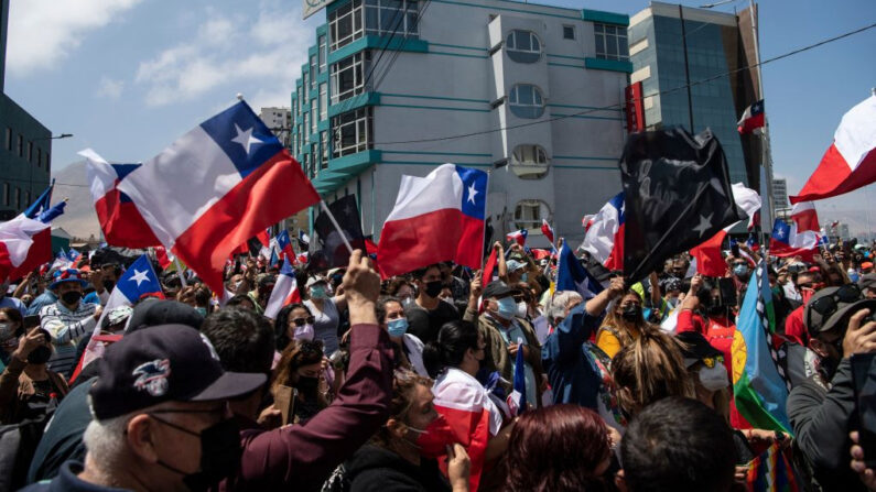 Personas agitando banderas nacionales chilenas protestan contra la migración ilegal en Iquique, Chile, el 25 de septiembre de 2021. (Martin Bernetti/AFP vía Getty Images)