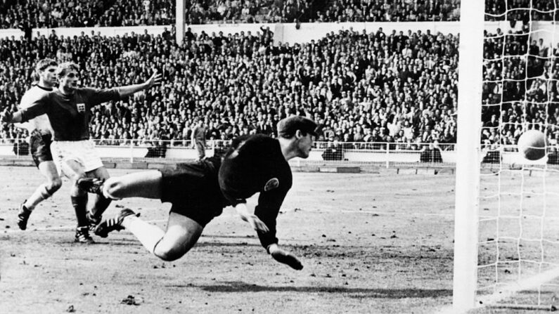El portero de Alemania Occidental, Hans Tilkowski, observa cómo el balón rebota en el travesaño tras un disparo del delantero inglés Geoff Hurst (no en la foto) mientras el delantero inglés Roger Hunt (con los brazos en alto) y el defensa de Alemania Occidental, Wolgang Weber, observan durante el tiempo extra de la final de la Copa del Mundo el 30 de julio de 1966 en el estadio de Wembley en Londres. (STF/AFP vía Getty Images)
