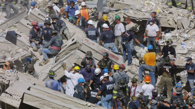 Los equipos de rescate y el personal médico intentan liberar a un sobreviviente de los restos del World Trade Center en la ciudad de Nueva York el 11 de septiembre de 2001. Los esfuerzos de rescate continuaron dos días después de que dos aviones se estrellaran contra las torres gemelas en un ataque terrorista, arrasándolos. (Mario Tama/Getty Images)