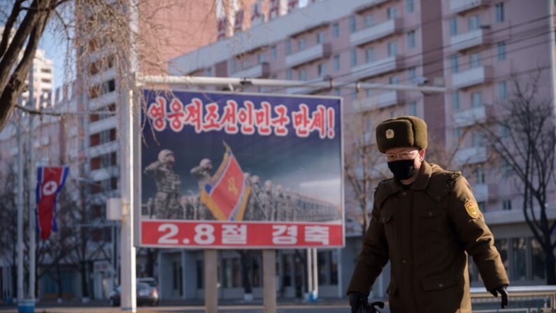 En una foto tomada el 8 de febrero de 2021, un soldado del Ejército Popular de Corea (EPC) pasa junto a un cartel expuesto en una calle de Pyongyang (Corea del Norte) que marca el 73º aniversario de la fundación del Ejército Popular de Corea. (Kim Won Jin/AFP vía Getty Images)