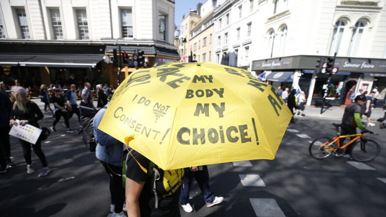 Un manifestante lleva un paraguas que dice, Mi cuerpo, mi elección, en referencia a las vacunas anti-COVID, durante la manifestación antibloqueo, Unidos por la libertad, celebrada para protestar contra el uso de pasaportes de vacunas en el Reino Unido, el 24 de abril de 2021, en Londres, Inglaterra. (Hollie Adams/Getty Images)