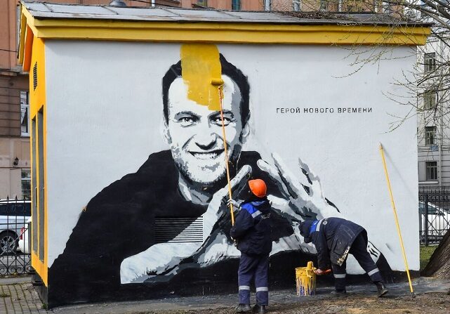 Un trabajador pinta sobre el grafiti del crítico del Kremlin encarcelado Alexei Navalny en San Petersburgo el 28 de abril de 2021. La inscripción dice: "El héroe de los nuevos tiempos". (Olga Maltseva/AFP vía Getty Images)
