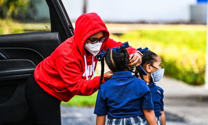 Una madre ajusta la mascarilla de su hijo antes de entrar en la escuela católica de San Lorenzo en el primer día de clase tras las vacaciones de verano en el norte de Miami el 18 de agosto de 2021. (Chandan Khanna/AFP vía Getty Images)