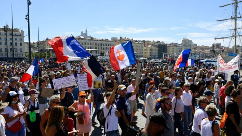 Personas marchan y sostienen pancartas durante una manifestación contra el pase sanitario obligatorio de covid-19 para acceder a la mayor parte del espacio público, en Marsella, sur de Francia, el 4 de septiembre de 2021. (Nicolas Tucat/AFP vía Getty Images)