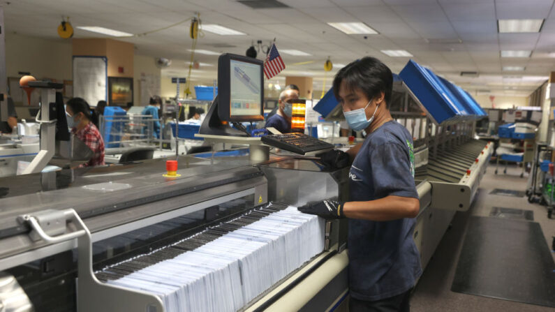 Un trabajador pasa una pila de papeletas de voto por correo a través de una máquina clasificadora en la oficina de registro de votantes del condado de Santa Clara el 25 de agosto de 2021 en San José, California.(Justin Sullivan/Getty Images)