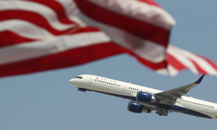 Imagen de archivo de un avión pasando tras una bandera estadounidense durante el despegue en el Aeropuerto Internacional de Los Ángeles el 22 de abril de 2013. (David McNew/Getty Images)