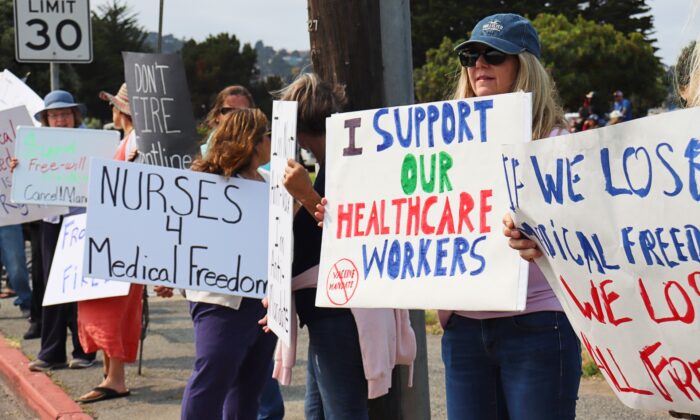 La gente sostiene carteles de apoyo a los trabajadores de la salud durante una manifestación en contra de las órdenes de vacunación en Monterey, California, el 26 de septiembre de 2021. (Cynthia Cai/The Epoch Times)