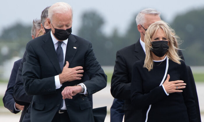 El presidente Joe Biden, a la izquierda, mira su reloj mientras él y la Primera Dama, Jill Biden, asisten a la ceremonia de traslado de los militares asesinados durante un atentado en Kabul, en la Base de la Fuerza Aérea de Dover, en Dover, Delaware, el 29 de agosto de 2021. (Saul Loeb/AFP a través de Getty Images)