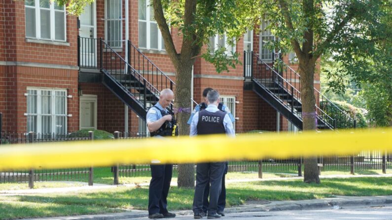 Dos policías hablan con un detective mientras investigan un tiroteo, en Chicago el 20 de agosto de 2021. (Cara Ding/The Epoch Times)