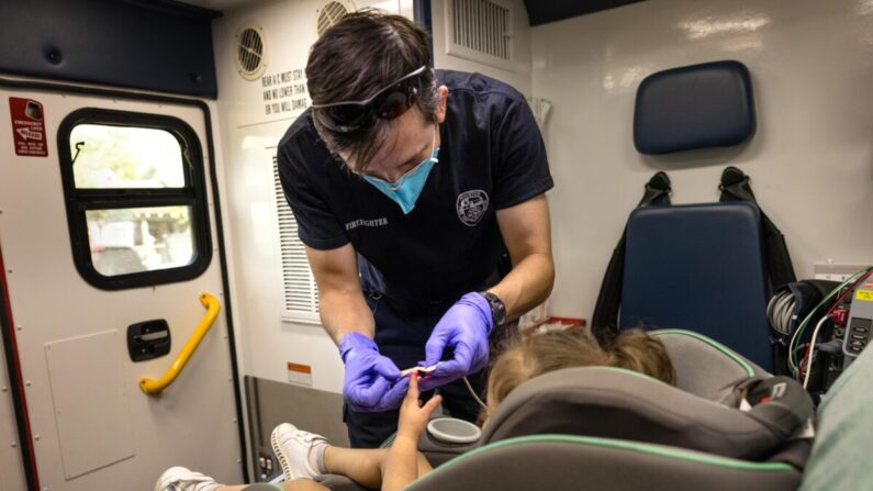 Un médico del Departamento de Bomberos de Houston se prepara para transportar a una niña de 2 años que ha dado positivo en la prueba COVID-19 a un hospital, en Houston, Texas, el 25 de agosto de 2021. (John Moore/Getty Images)
