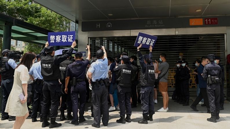 Agentes de policía observan a las personas que se reúnen en la sede de Evergrande en Shenzhen, sureste de China, el 16 de septiembre de 2021, mientras el gigante inmobiliario chino dijo que se enfrenta a "dificultades sin precedentes", pero negó los rumores de que está a punto de quebrar. (NOEL CELIS/AFP vía Getty Images)