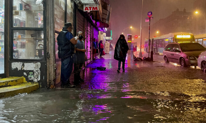 Algunas personas se abren paso bajo la lluvia de los restos del huracán Ida en el barrio del Bronx de Nueva York el 1 de septiembre de 2021. (David Dee Delgado/Getty Images)